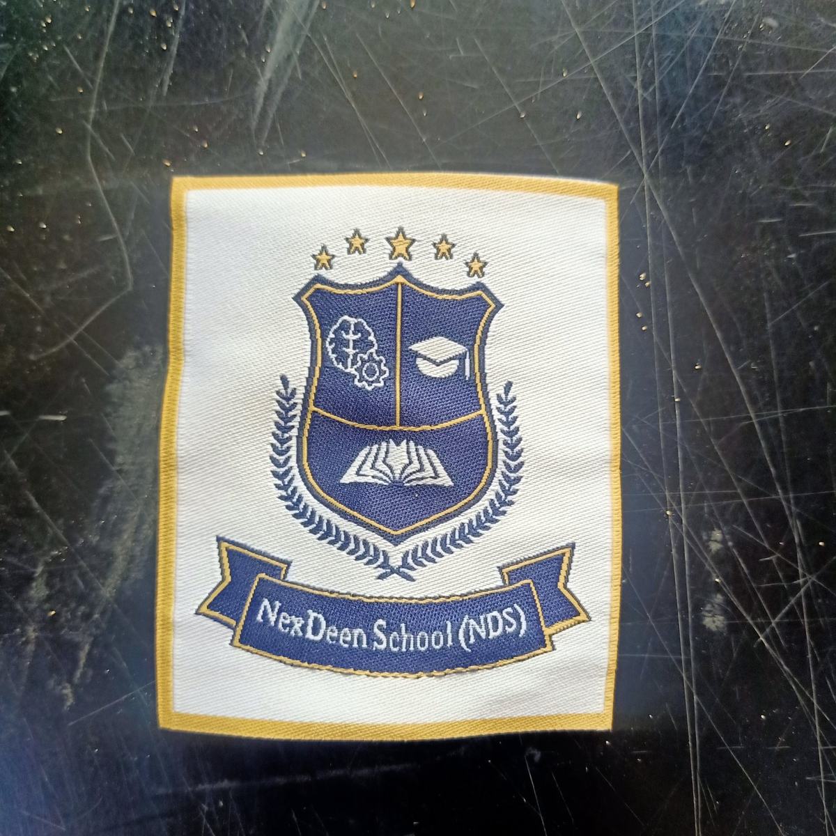 Woven school badge for NexDeen School NDS, navy and gold crest