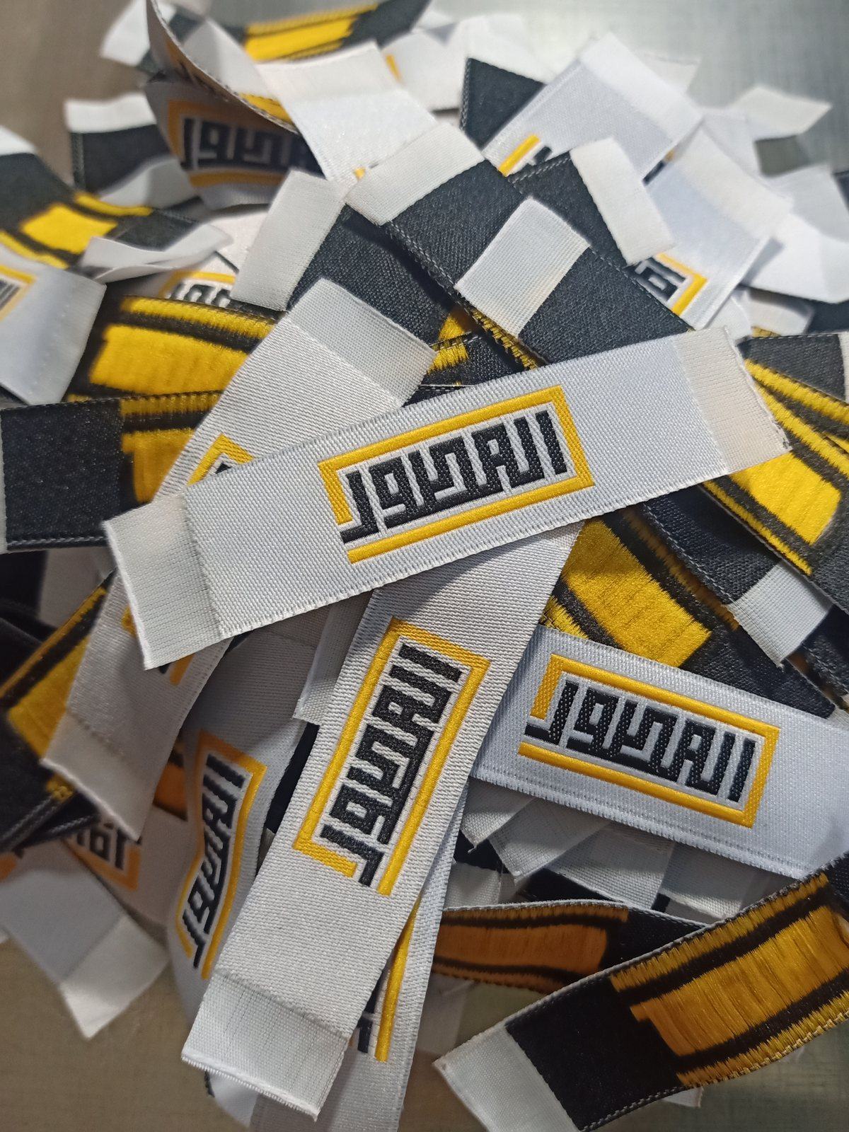 Pile of woven ribbon labels in bold yellow, black and white